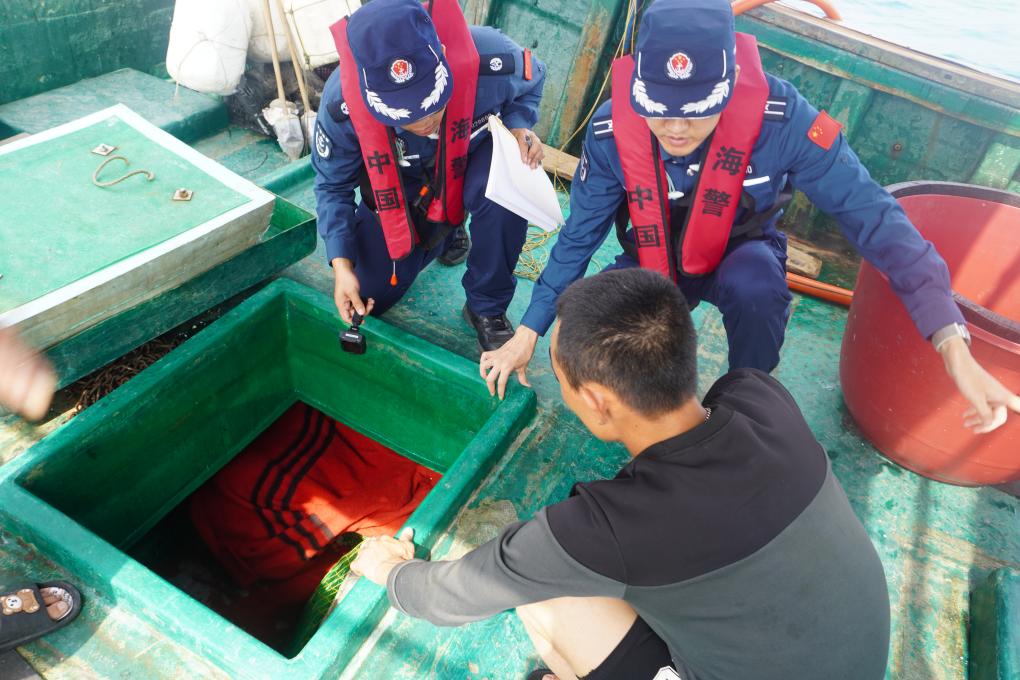 图为5月15日海警执法员对渔船进行检查。